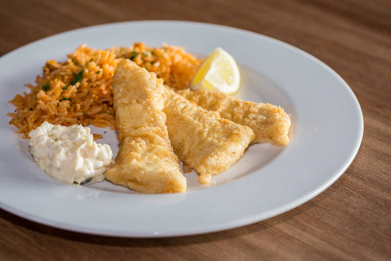 Filetes de pescada com arroz de berbigão e molho tártaro servidos num restaurante de peixe em Lisboa.